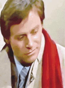 a man with a red scarf around his neck is looking down