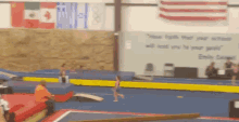 emily george 's quote hangs on a wall behind a girl on a balance beam