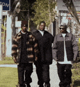 three men are walking down a sidewalk in front of a sign that says ' lon '