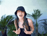 a woman wearing a black hat and a black tank top is making a funny face
