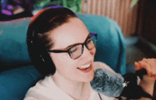 a woman wearing glasses and headphones is smiling while holding a microphone