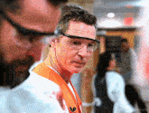 a man wearing safety goggles and an orange vest with the letter w on it