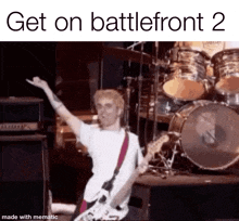 a man is playing a guitar on a stage with a drum set in the background .