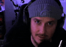a man wearing headphones and a beanie is looking at the camera