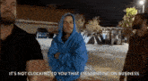 a man in a blue hoodie is standing in a parking lot talking to another man .