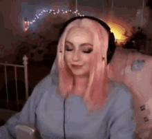 a woman with pink hair is wearing headphones while sitting on a chair .