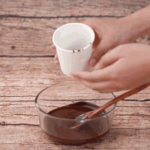 a person is pouring a cup of liquid into a glass bowl