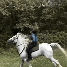 a woman riding a white horse in a field