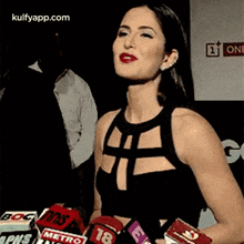 a woman in a black dress is talking into microphones .