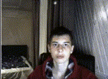 a young man wearing glasses and a red sweater is sitting in a chair