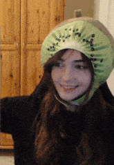 a woman wearing a kiwi hat is smiling at the camera
