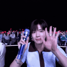 a man is holding a blue microphone in front of a crowd of people