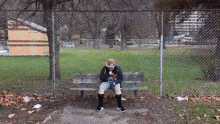 a person sitting on a bench wearing a hoodie that says ' i love ny '