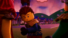 a lego character with a scarf around his neck stands in front of a village