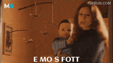 a woman holding a baby with the words emo s fott written below her