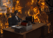 a man sits at a desk in front of a wall that is on fire and a sign that says ' emergency management '