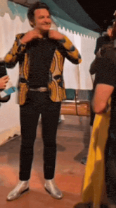 a man wearing a yellow jacket and black pants is standing in a room