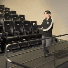 a man in a polo shirt is standing in front of a row of black seats in a theater