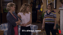 three women are standing in a living room with the words it 's always open
