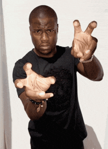 a man in a black shirt is making a hand gesture with his hands