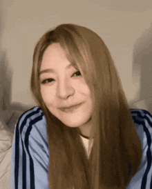 a woman with long blonde hair is wearing a blue and white striped shirt
