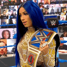 a woman with blue hair is holding a wrestling championship belt