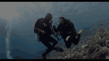 a couple of scuba divers are in the water and one has the word scuba on his back