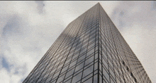 looking up at a tall building with a cloudy sky behind it