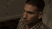 a man in a plaid shirt is crying while holding a hammer .