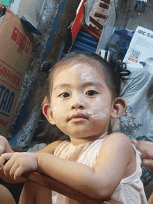 a little girl sitting in front of a sanyo box
