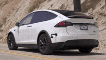 a white tesla model x is parked on a road