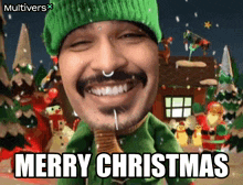 a man wearing a green hat and sweater says merry christmas in front of a gingerbread house
