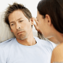 a woman is touching a man 's ear while he looks at her