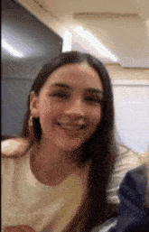 a woman is smiling and looking at the camera while sitting in a room .