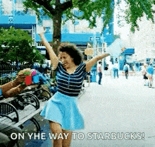 a woman in a blue skirt is dancing in a park with the words on the way to starbucks below her