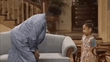 a woman and a little girl are standing next to each other in front of a couch in a living room .