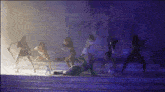 a group of women are dancing on a stage with a purple background