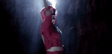 a pink power ranger is standing in the dark with his arms in the air .