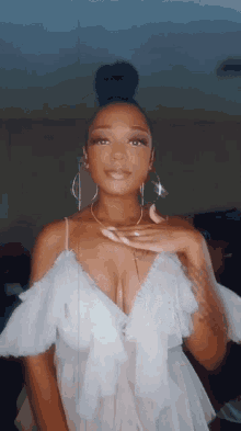a woman wearing a white dress with ruffles and hoop earrings