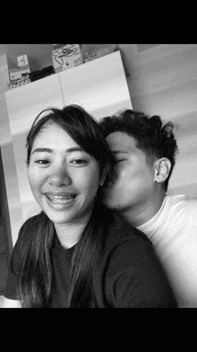 a black and white photo of a man kissing a woman