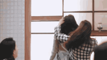 two women hugging each other in front of a window .