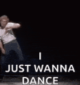 a man is dancing on a stage with the words `` i just wanna dance '' written on it .