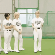 a group of young men wearing baseball uniforms are standing on a baseball field .