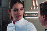 a woman in a white uniform looks at another woman