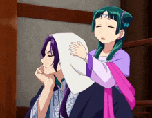 a girl is putting a towel on the head of a man
