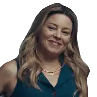 a woman wearing a blue shirt and a gold necklace smiles for the camera