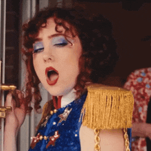a woman in a blue and gold costume with fringe on the shoulder