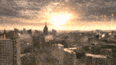 an aerial view of a city at sunset with the sun shining brightly through the clouds