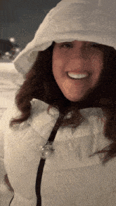 a woman wearing a white jacket with a hood smiles