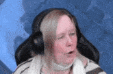 a woman is wearing headphones and making a funny face while sitting in a chair .